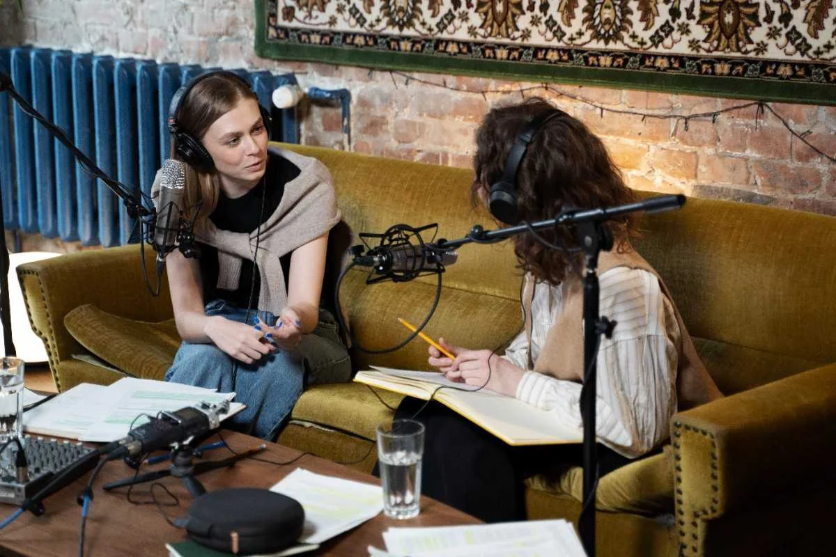 Two women discussing Media and Journalism Abbreviations while recording a podcast in a studio setting.