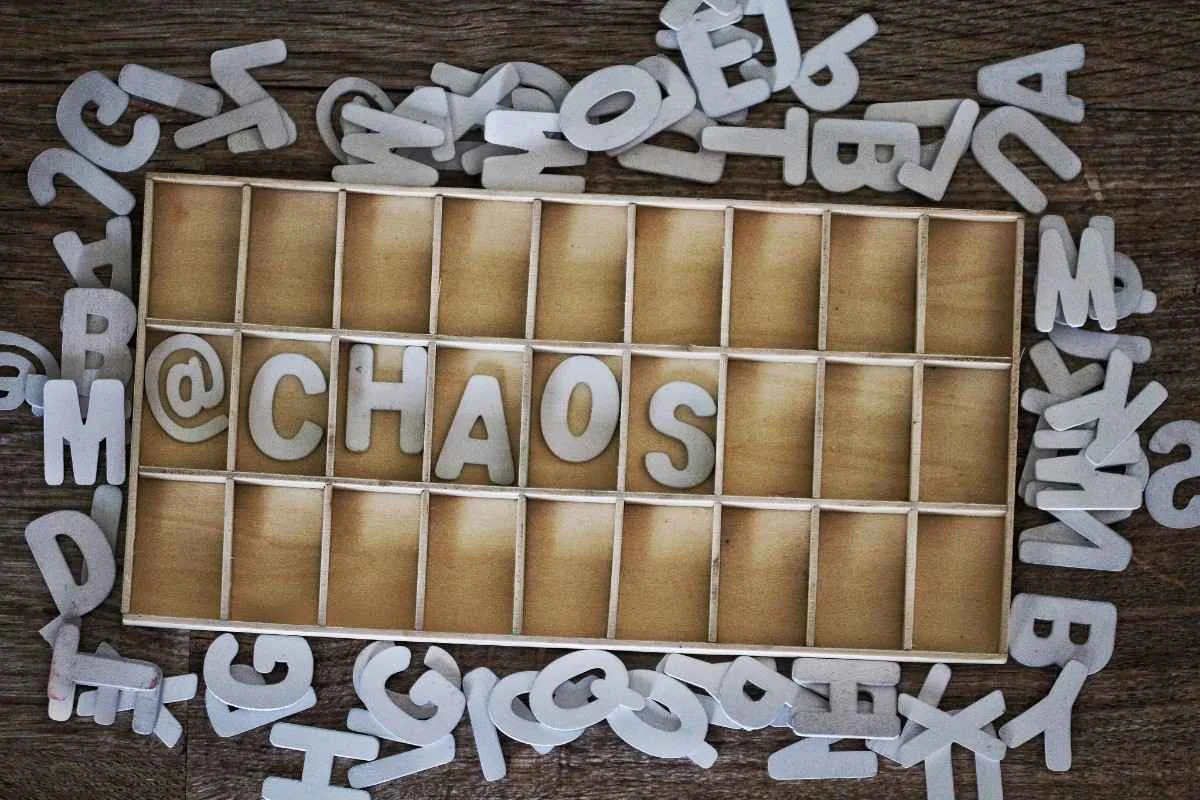 A collection of wooden letter tiles scattered on a wooden surface, with a focus on the word "CHAOS" placed in a wooden box. Acronyms Starting with C: Common, Technical & Business Terms